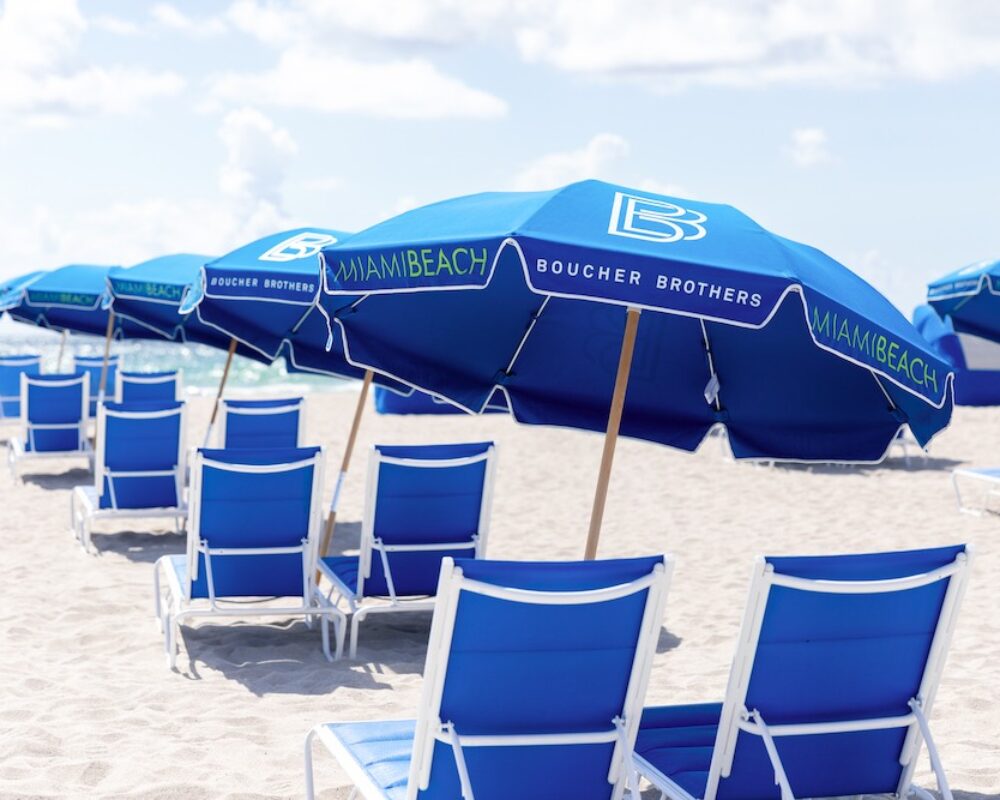 Guests relaxing on blue loungers along the surf.