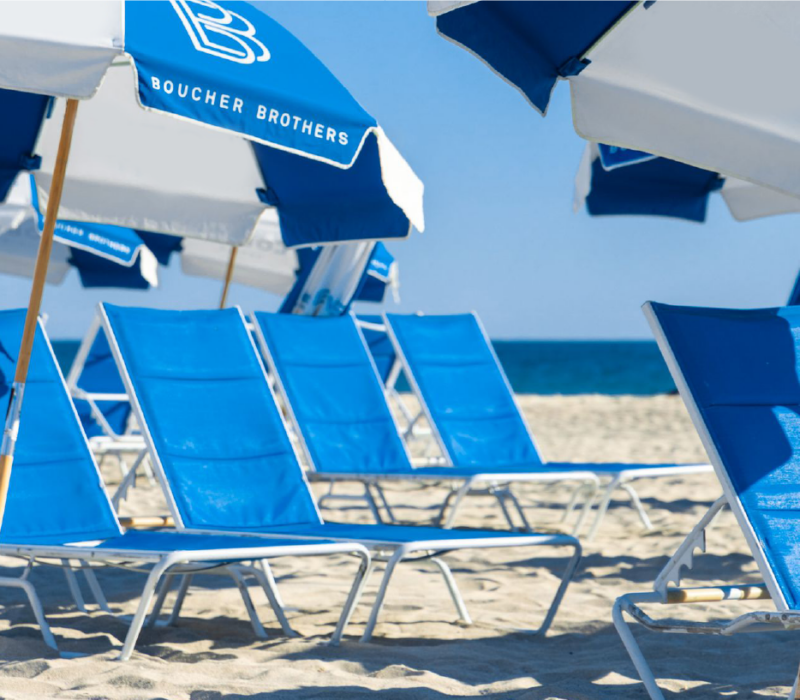 Boucher Brothers blue umbrellas in a neat row along the shore.