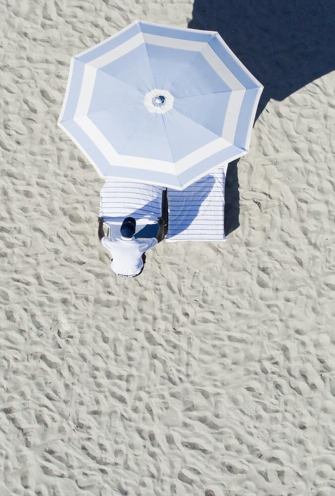 A queen-sized day bed dressed in white on the sand.