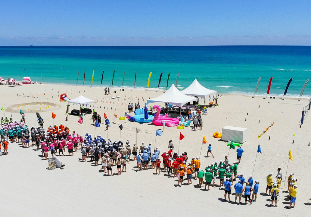 A corporate group mid-game on the sand, laughing through a team relay.