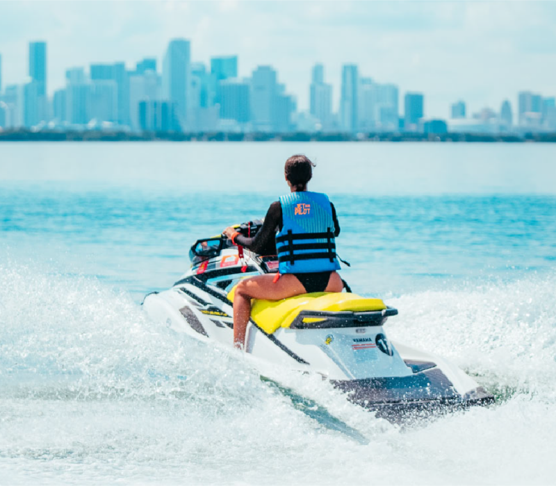 A jet skier crossing Haulover's clear water with the Miami skyline beyond.