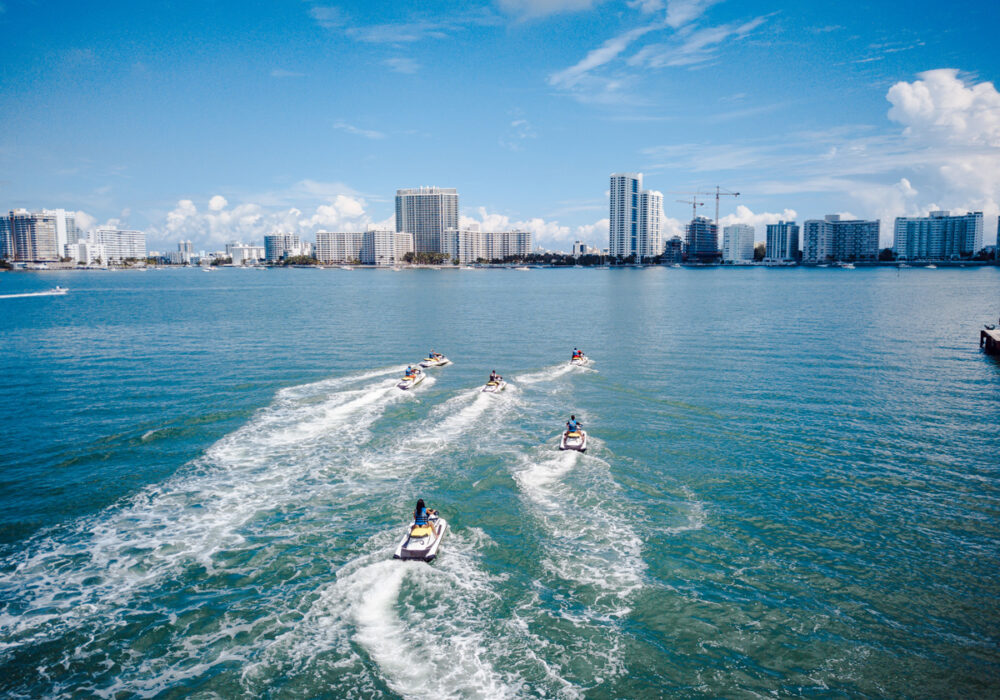 Jet skis and paddleboards cutting across clear shallows.
